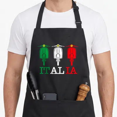 Italia scooter apron - Three scooters in green white and red above ITALIA text — shown on a black cotton canvas apron against a white background