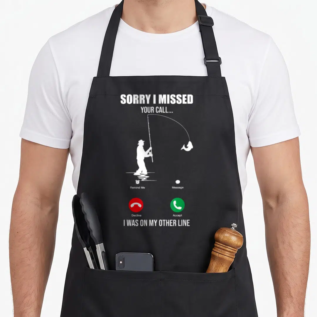 Sorry missed fishing aprons - Fisherman silhouette with phone interface icons and text SORRY I MISSED YOUR CALL — shown on a black cotton canvas apron against a white background