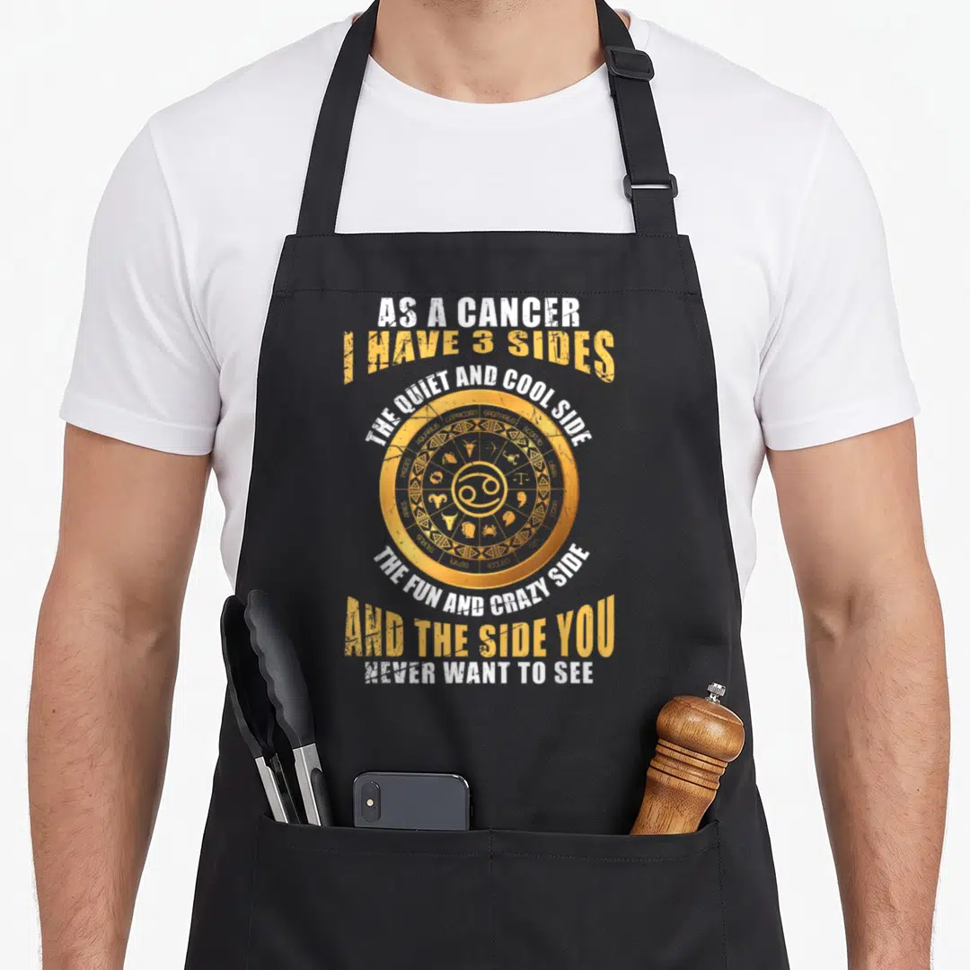 Cancer character aprons - Yellow zodiac wheel with Cancer symbol and text listing three personality sides — shown on a black cotton canvas apron against a white background