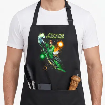 Lantern comics apron - Green Lantern text with hero in green suit firing green blast and orange sphere — shown on a black cotton canvas apron against a white background