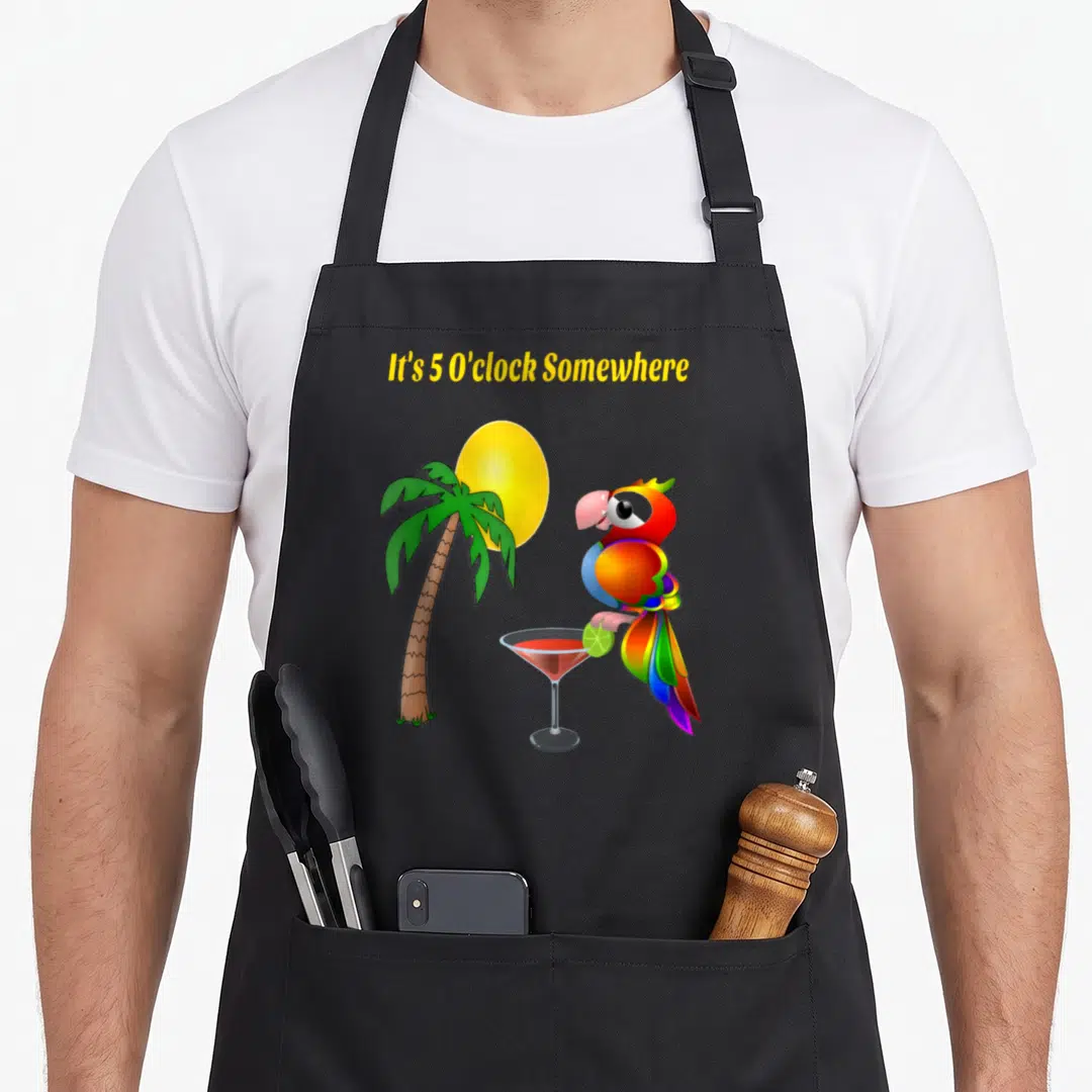 Oclock funny parrot apron - Cartoon parrot on cocktail glass with palm tree and yellow text It's 5 O'clock Somewhere — shown on a black cotton canvas apron against a white background