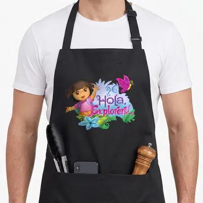 Dora spring apron - Dora waving next to Hola Explorers text with butterfly and blue flower — shown on a black cotton canvas apron against a white background