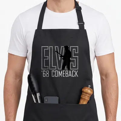Presley comeback apron - White dotted ELVIS text with guitar player silhouette and ''68 COMEBACK below — shown on a black cotton canvas apron against a white background
