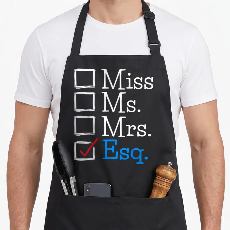 Exam lawyer apron - Checklist with Miss Ms Mrs unchecked and Esq checked in blue with red mark — shown on a black cotton canvas apron against a white background