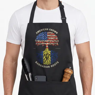 Barbadian american flag apron - Tree with USA flag canopy and Barbados flag roots, text AMERICAN GROWN BARBADIAN ROOTS — shown on a black cotton canvas apron against a white background