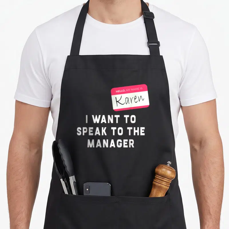 Speak halloween apron - Pink name tag Hello My Name Is Karen with I Want to Speak to the Manager text — shown on a black cotton canvas apron against a white background
