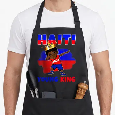 Haiti king apron - Cartoon boy dabbing in gold crown with Haiti 1804 Young King text over blue red flag strokes — shown on a black cotton canvas apron against a white background