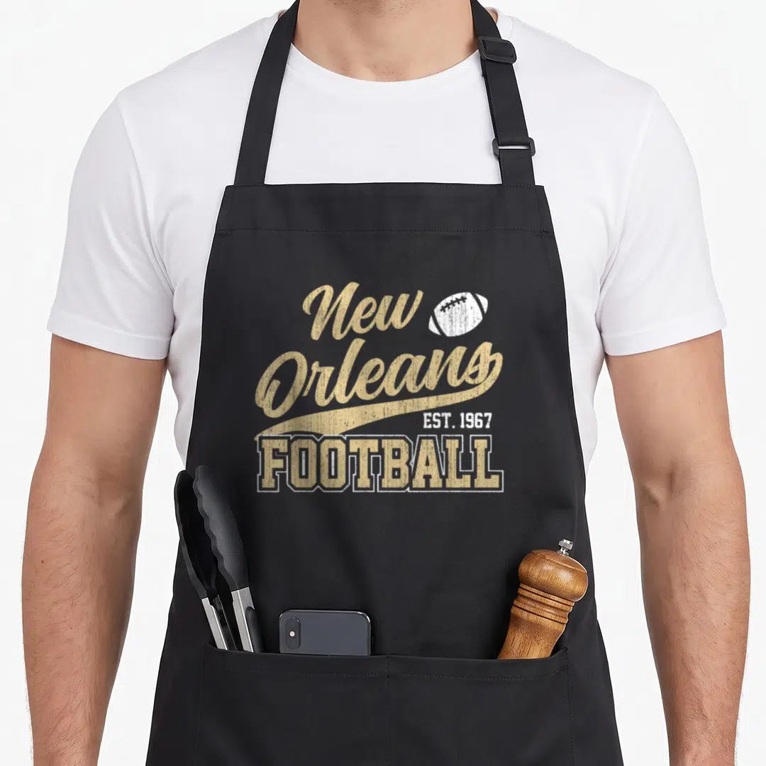 Distressed new orleans apron - Gold script New Orleans text with white football and EST 1967 football label — shown on a black cotton canvas apron against a white background