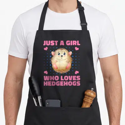 Funny hedgehog pet apron - Cartoon hedgehog with pink text and blue dots on black apron — shown on a black cotton canvas apron against a white background