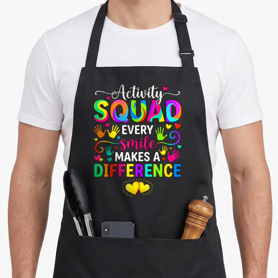 Professional week activity apron - Stacked text Activity SQUAD EVERY smile MAKES A DIFFERENCE with colorful handprints — shown on a black cotton canvas apron against a white background