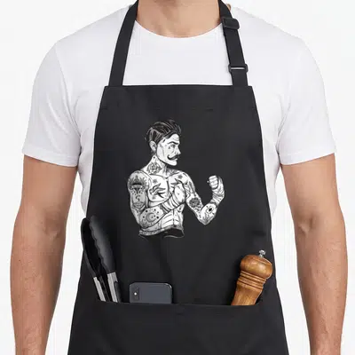 Boxing boho apron - Tattooed boxer facing right with OLD SCHOOL arm ink and hand wraps in black and white line art — shown on a black cotton canvas apron against a white background