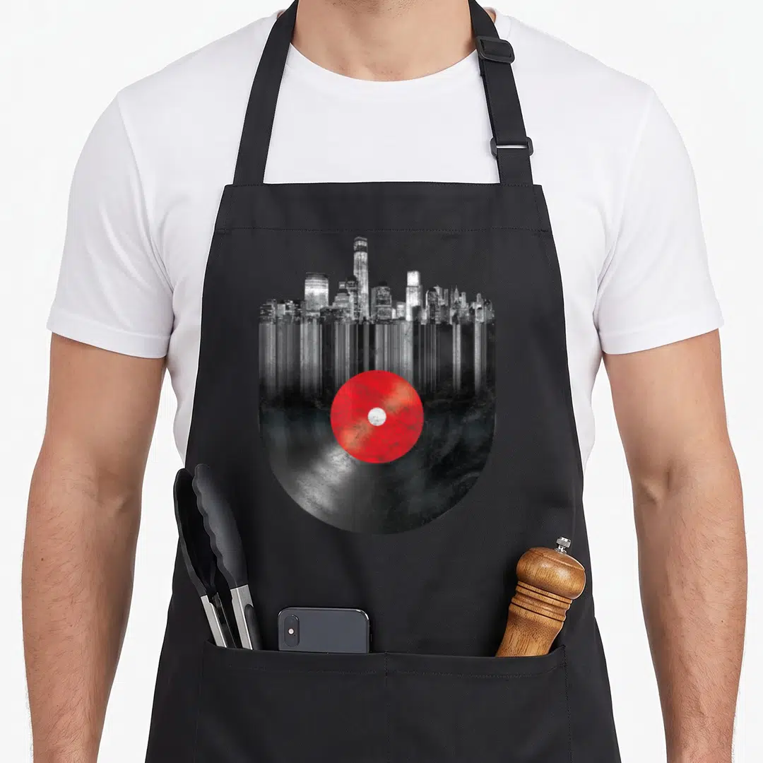 Vinyl new york apron - Mirrored NYC skyline with red vinyl record centered on black and grey photo print — shown on a black cotton canvas apron against a white background
