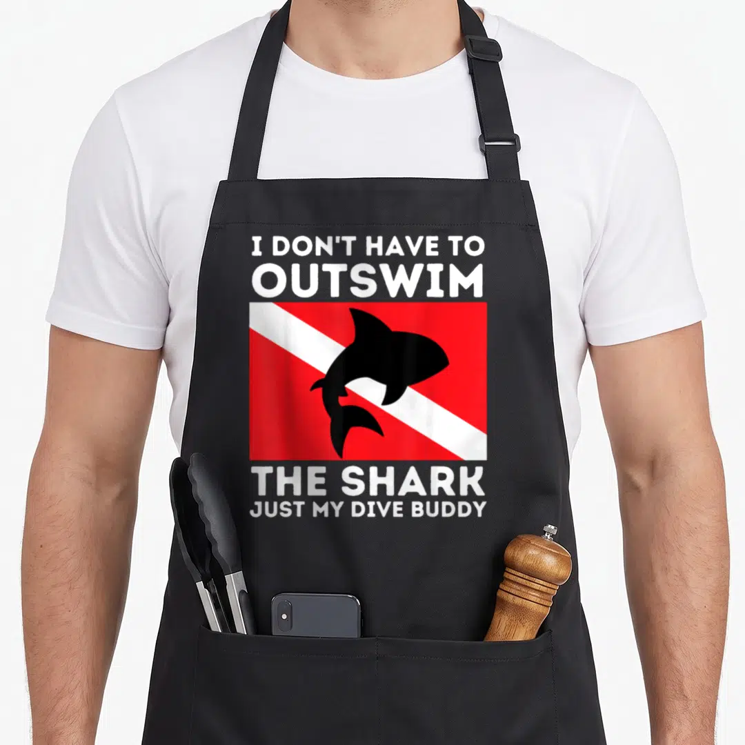 Outswim buddy aprons - I DON'T HAVE TO OUTSWIM THE SHARK text with black shark on red and white flag — shown on a black cotton canvas apron against a white background