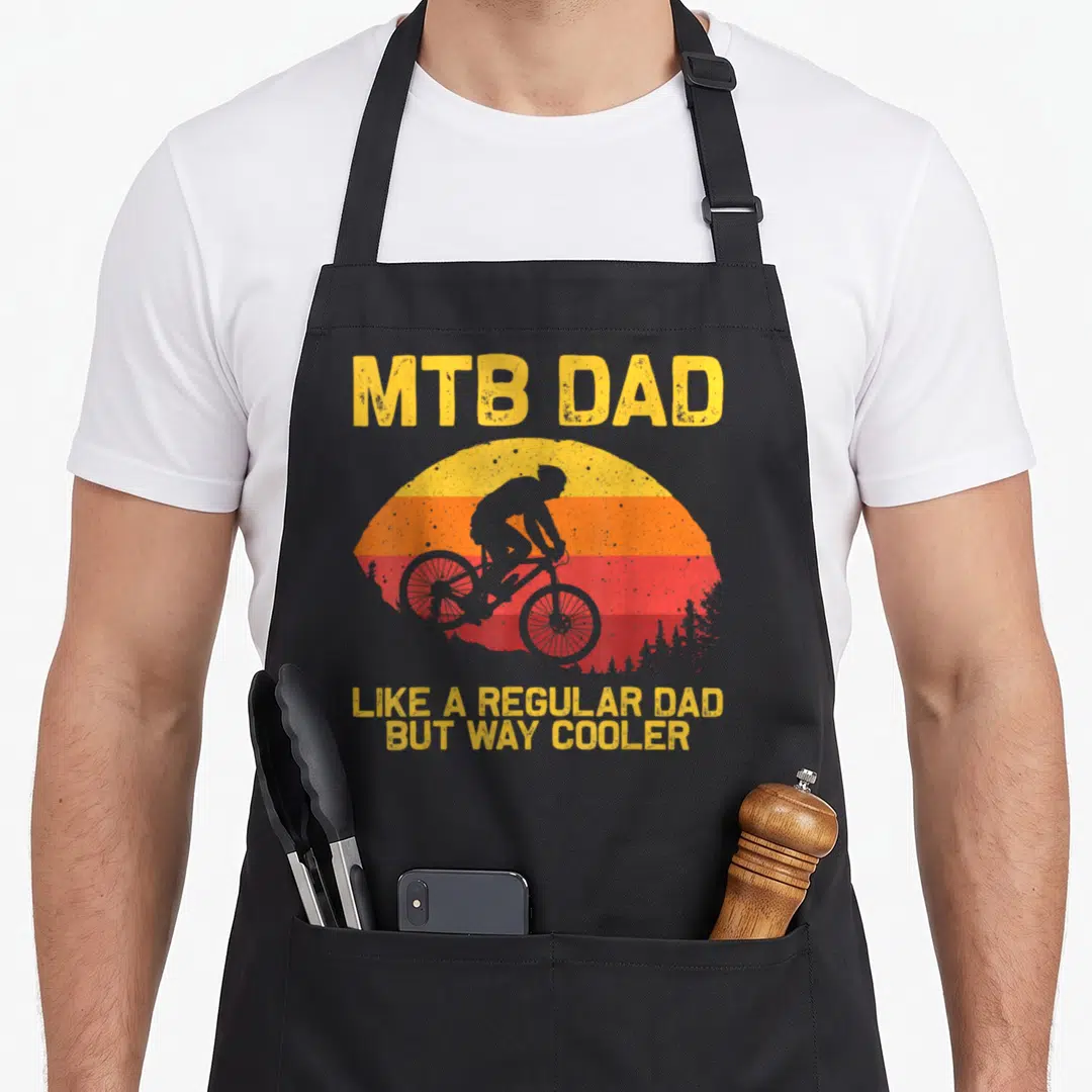 Father bicycle apron - Retro sunset with grey mountain biker silhouette and yellow MTB DAD text on black fabric — shown on a black cotton canvas apron against a white background