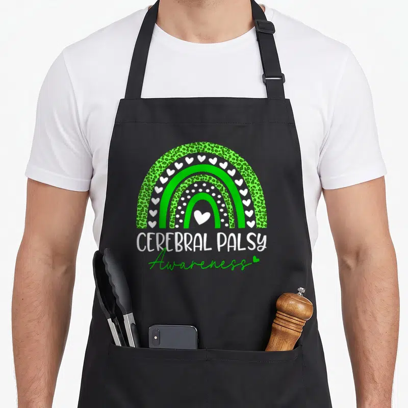 Cerebral leopard apron - Green leopard rainbow with white hearts and Cerebral Palsy Awareness text — shown on a black cotton canvas apron against a white background