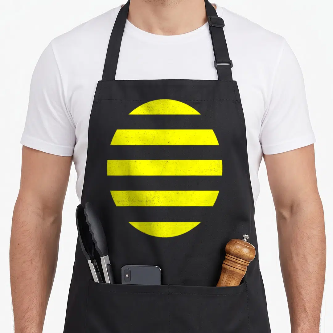 Costume bee apron - Minimalist yellow circle divided into five horizontal grey-striped segments — shown on a black cotton canvas apron against a white background