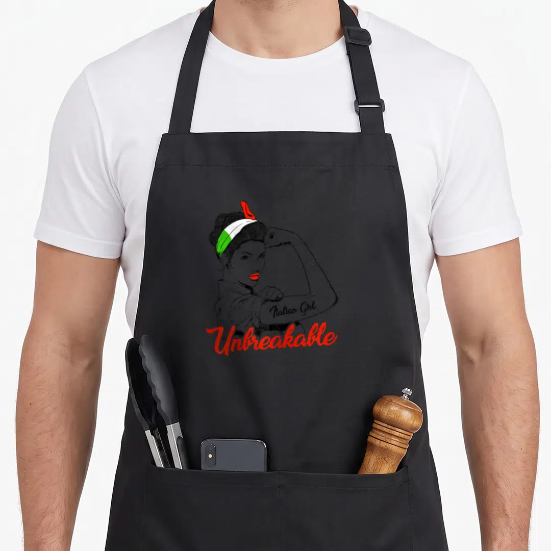 Unbreakable italy apron - Woman flexing arm wearing Italian flag headband with Unbreakable text below — shown on a black cotton canvas apron against a white background
