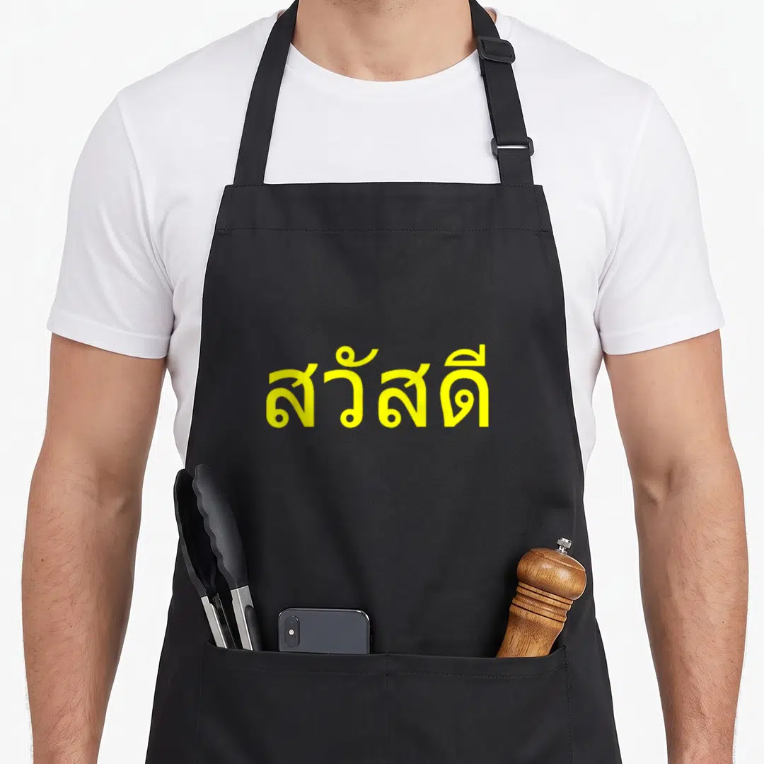 Language thai girl apron - Yellow Thai script reading Sawasdee on grey background — shown on a black cotton canvas apron against a white background