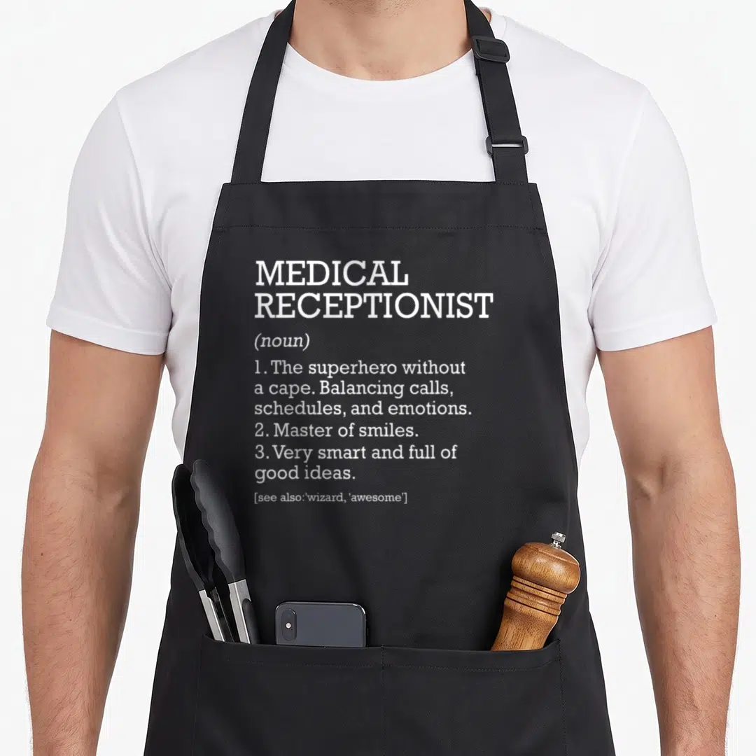 Definition receptionist apron - White typography defining medical receptionist as a superhero balancing calls — shown on a black cotton canvas apron against a white background