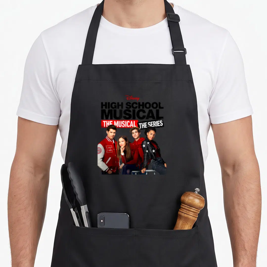 Cast school apron - HIGH SCHOOL MUSICAL THE MUSICAL THE SERIES text above four people in black red white photo — shown on a black cotton canvas apron against a white background