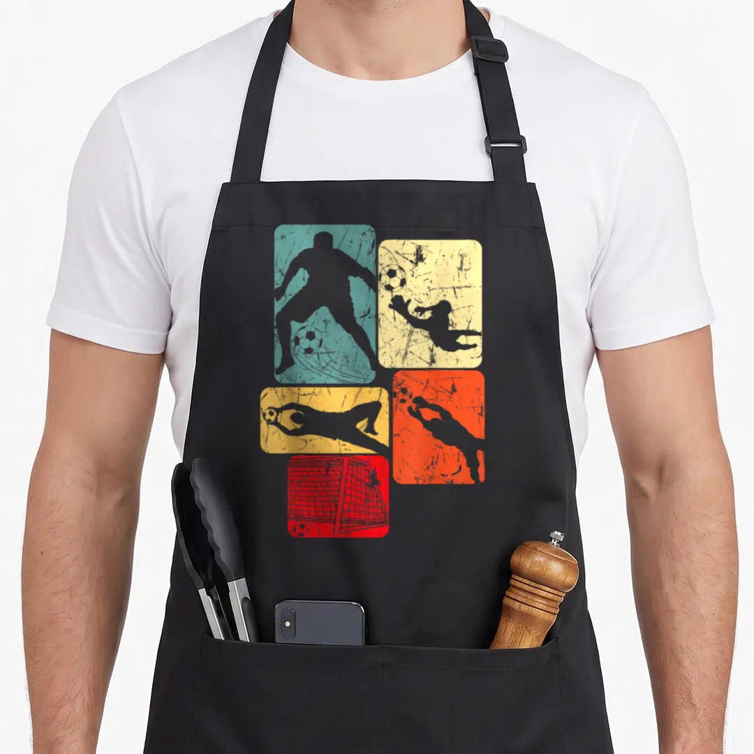 Youth goalie apron - Four colored distressed panels with grey soccer player silhouettes, balls, and goal net — shown on a black cotton canvas apron against a white background