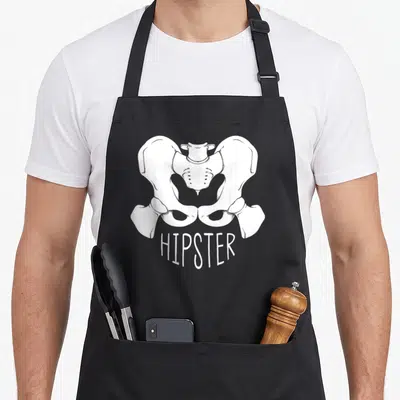 Orthopaedic surgeon apron - White line drawing of a human pelvis positioned above the text HIPSTER in minimalist style — shown on a black cotton canvas apron against a white background