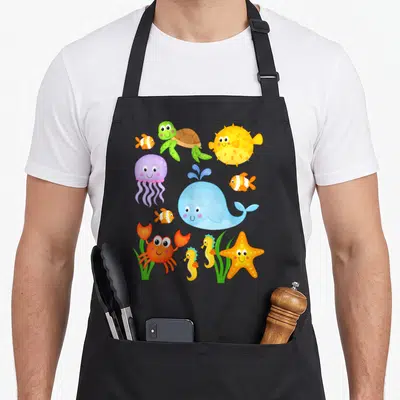 Octopus crab apron - Cartoon blue whale surrounded by smiling jellyfish, crab, seahorse, and starfish in bright colors — shown on a black cotton canvas apron against a white background