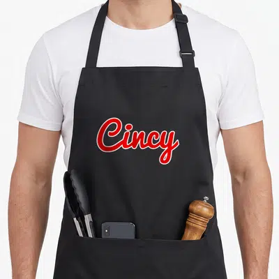 Ohio cincinnati apron - Red script Cincy text with white outline on grey background — shown on a black cotton canvas apron against a white background