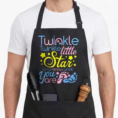 Twinkle honestly apron - Stacked text Twinkle Twinkle little Star with blue pink yellow colors and two baby footprints — shown on a black cotton canvas apron against a white background