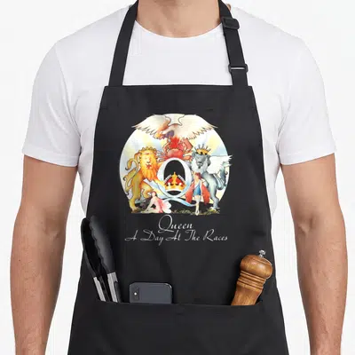 Race queen apron - Queen crest with Q, animals, figures, and A Day At The Races text — shown on a black cotton canvas apron against a white background