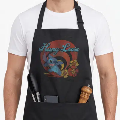 Hang loose apron - Retro Stitch surfing design with Hang Loose text and hibiscus flowers on red circle — shown on a black cotton canvas apron against a white background