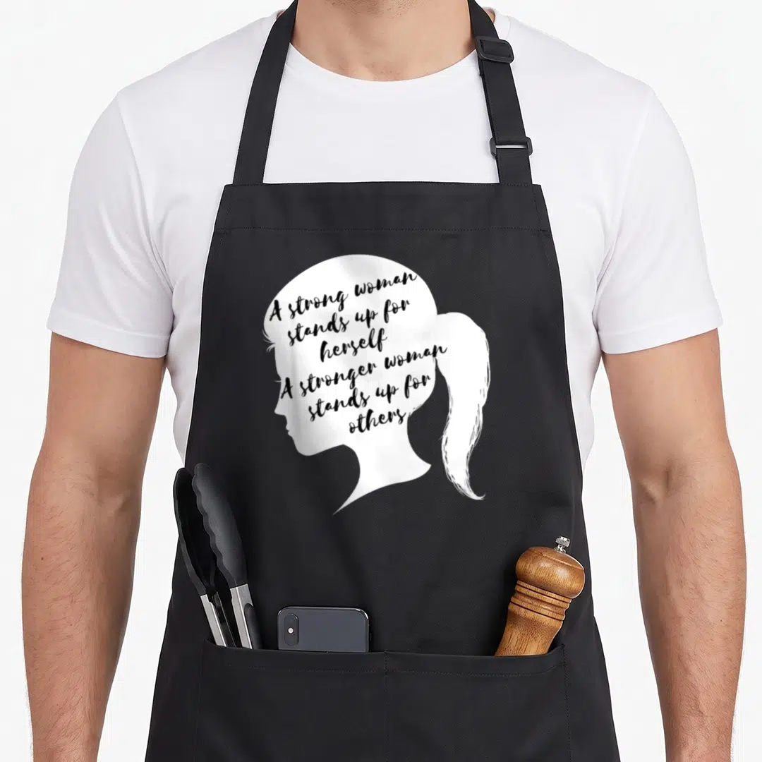 Strong social apron - White female silhouette facing left with black text about standing up for self and others — shown on a black cotton canvas apron against a white background