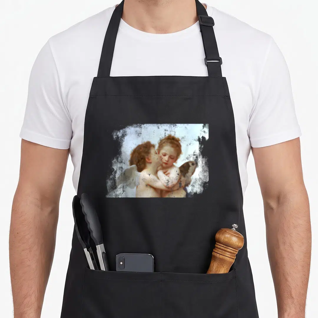 Kissing angels and aprons - Two cherubs embracing and kissing in a distressed rectangular photo with white, peach — shown on a black cotton canvas apron against a white background