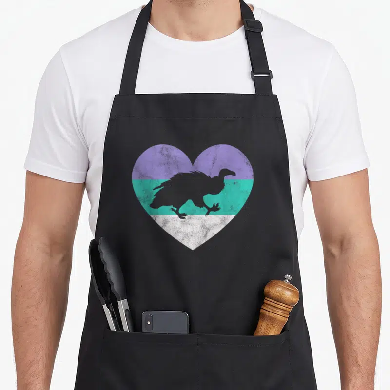 Funny crazy vulture lady apron - Grey vulture silhouette on heart with purple teal and white horizontal bands — shown on a black cotton canvas apron against a white background