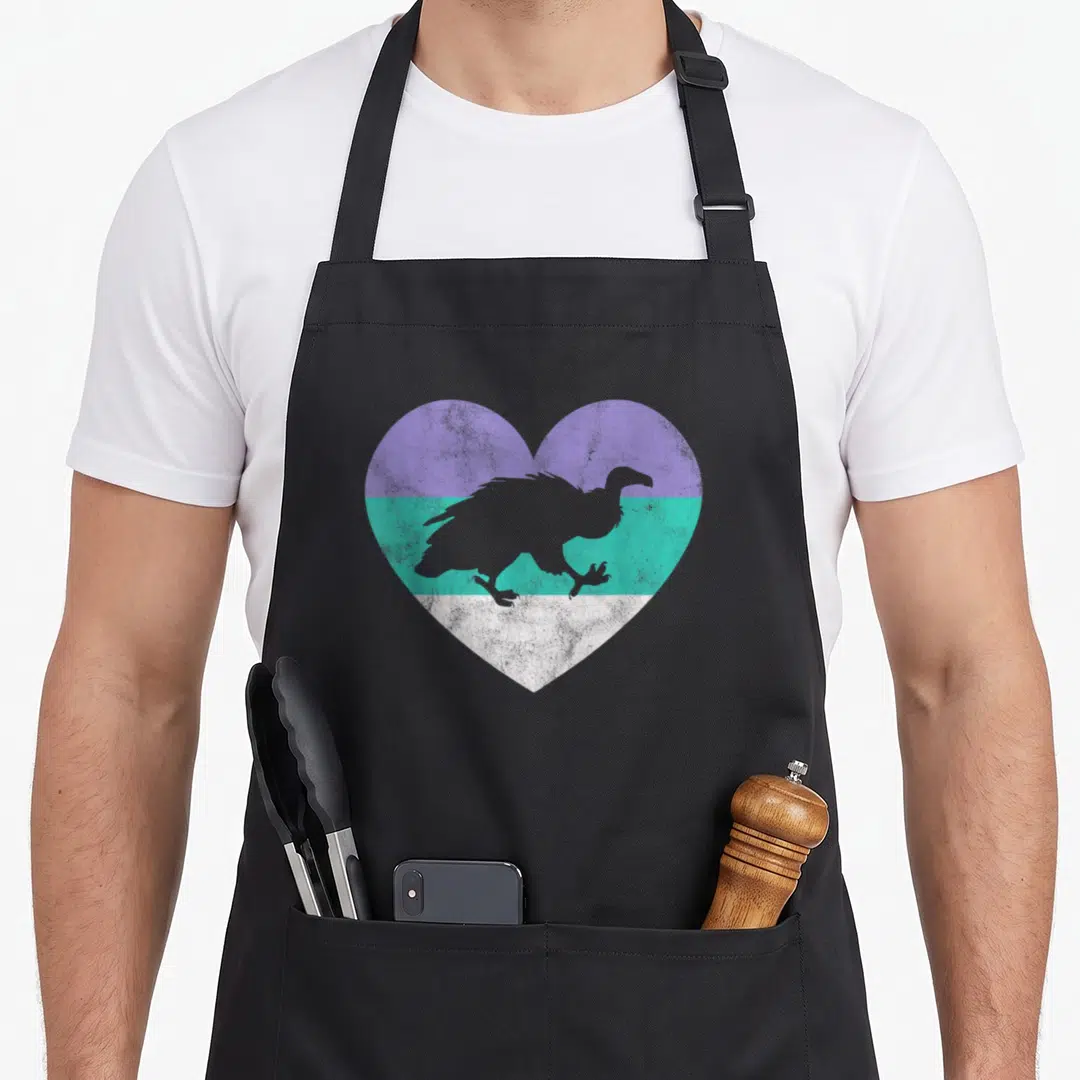 Funny crazy vulture lady apron - Grey vulture silhouette on heart with purple teal and white horizontal bands — shown on a black cotton canvas apron against a white background
