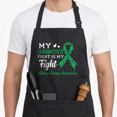 Daughter fight kidney disease awareness apron - Stacked white and green text next to a ribbon made of small green — shown on a black cotton canvas apron against a white background