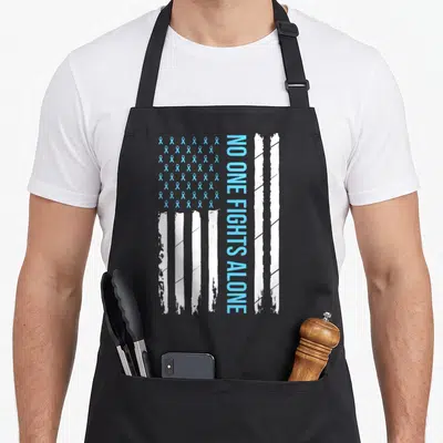 Blue ribbon apron - Vertical NO ONE FIGHTS ALONE text next to light blue ribbon grid and distressed white stripes — shown on a black cotton canvas apron against a white background