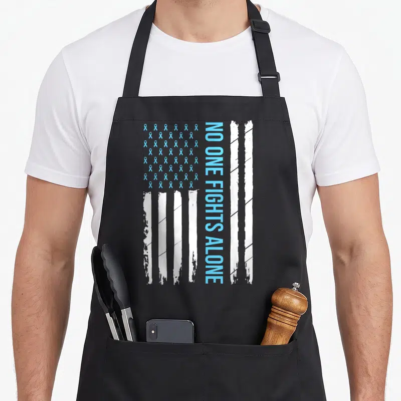 Blue ribbon apron - Vertical NO ONE FIGHTS ALONE text next to light blue ribbon grid and distressed white stripes — shown on a black cotton canvas apron against a white background