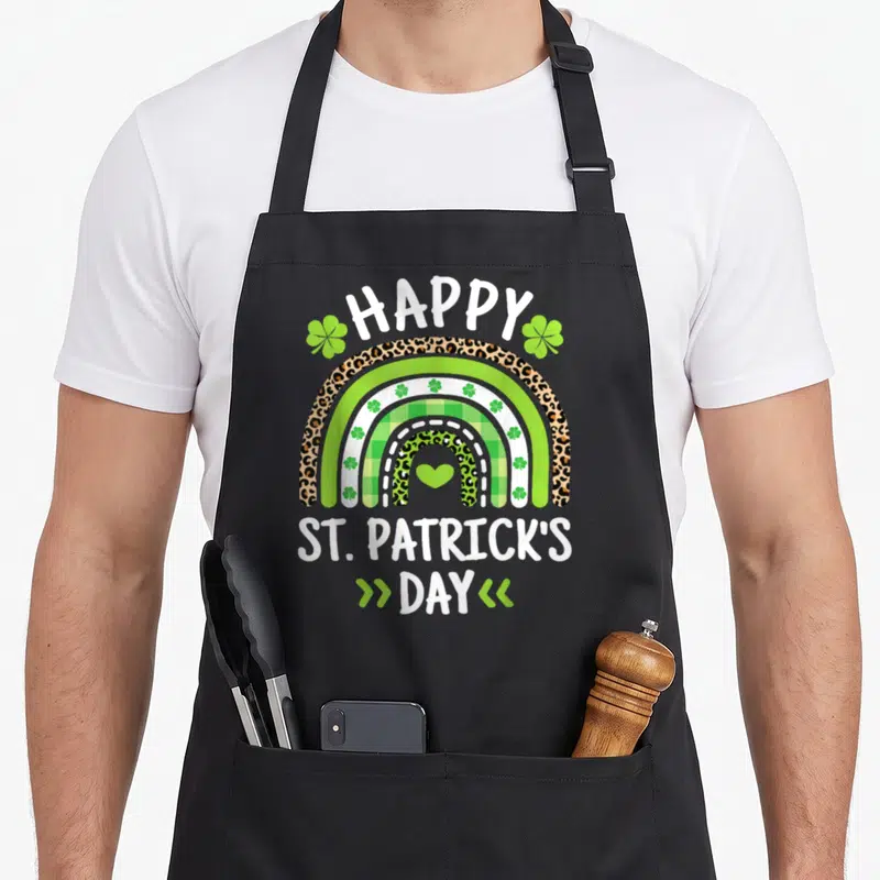 Rainbow irish aprons - Leopard print rainbow with shamrocks and green heart under Happy St Patricks Day text — shown on a black cotton canvas apron against a white background