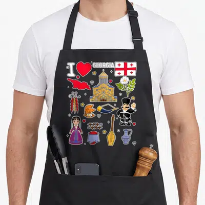 Hand georgian girl apron - Cartoon collage of Georgia map, flag, traditional girl, and cultural symbols in red and gold — shown on a black cotton canvas apron against a white background