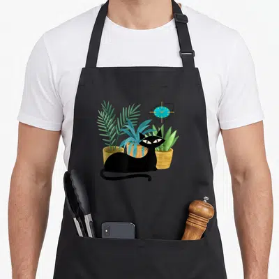 Botanical modern apron - Black cat sits before three potted plants and a blue clock in cartoon style — shown on a black cotton canvas apron against a white background