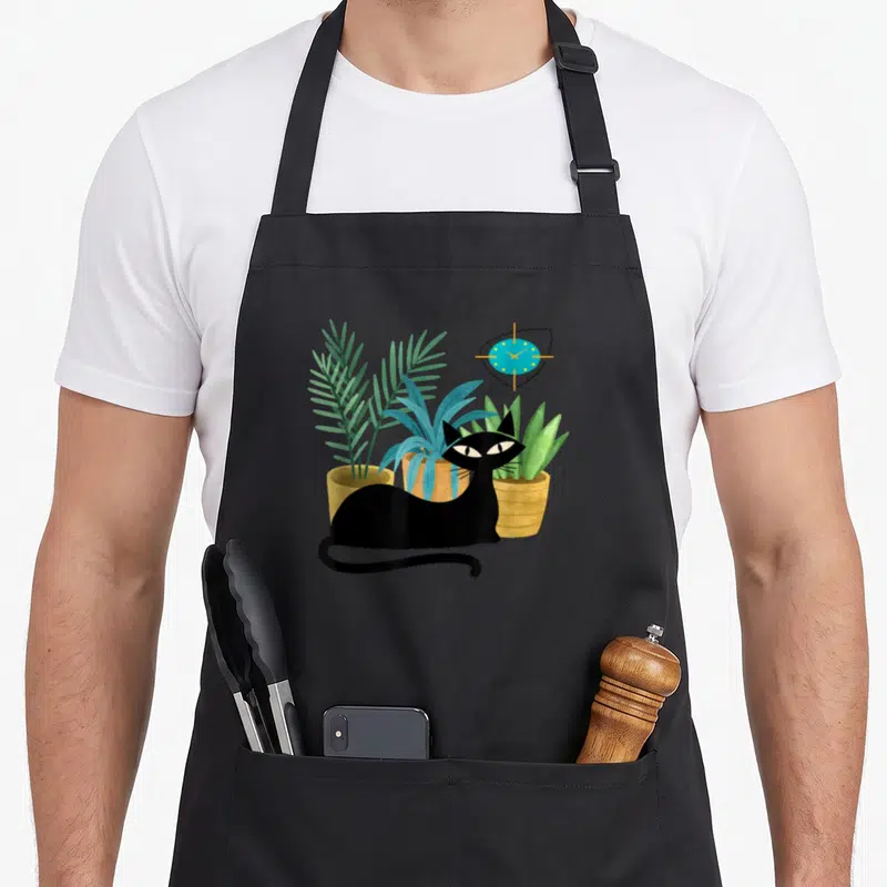 Botanical modern apron - Black cat sits before three potted plants and a blue clock in cartoon style — shown on a black cotton canvas apron against a white background