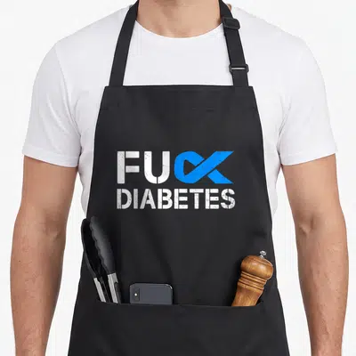 Diabete ribbon apron - FUC DIABETES text with blue awareness ribbon replacing K in distressed white font — shown on a black cotton canvas apron against a white background