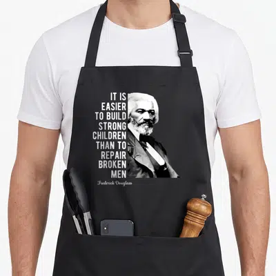 Frederick black history apron - Stacked quote text next to minimalist portrait of Frederick Douglass in grayscale — shown on a black cotton canvas apron against a white background