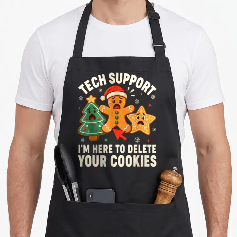 Delete women's christmas aprons - Tech support delete cookies text with gingerbread man and Christmas tree graphics — shown on a black cotton canvas apron against a white background