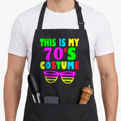 Costume 60s apron - Stacked multi-colored text reading 70s costume above pink and yellow shutter shades — shown on a black cotton canvas apron against a white background