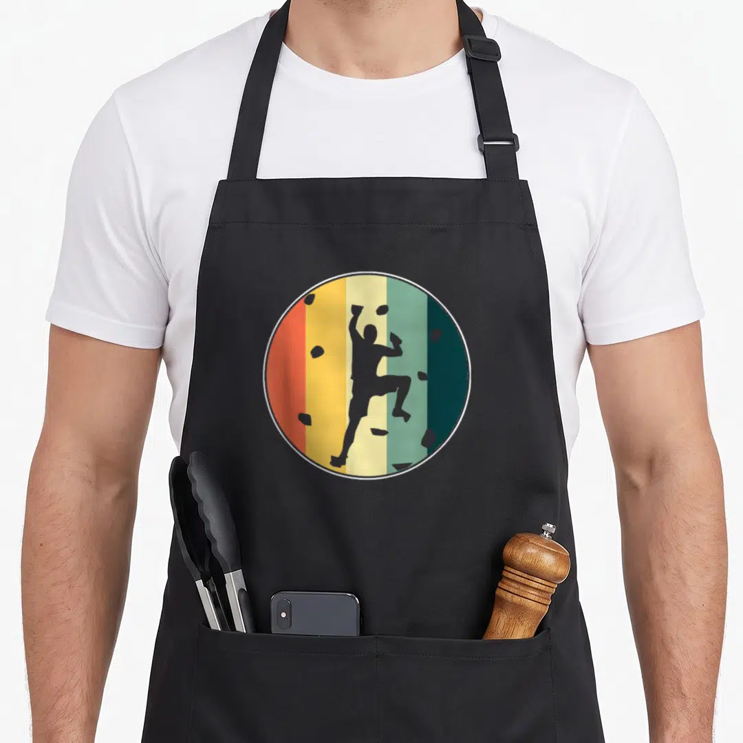 Wall bouldering apron - Grey climber silhouette over orange yellow and green vertical stripes with scattered rocks — shown on a black cotton canvas apron against a white background