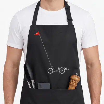Bicycle safety apron - White line-art tricycle with long pole and red flag, no text — shown on a black cotton canvas apron against a white background