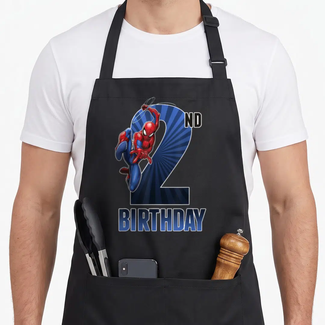 Swinging 2nd apron - Spider-Man cartoon figure over blue number 2 with ND BIRTHDAY text — shown on a black cotton canvas apron against a white background
