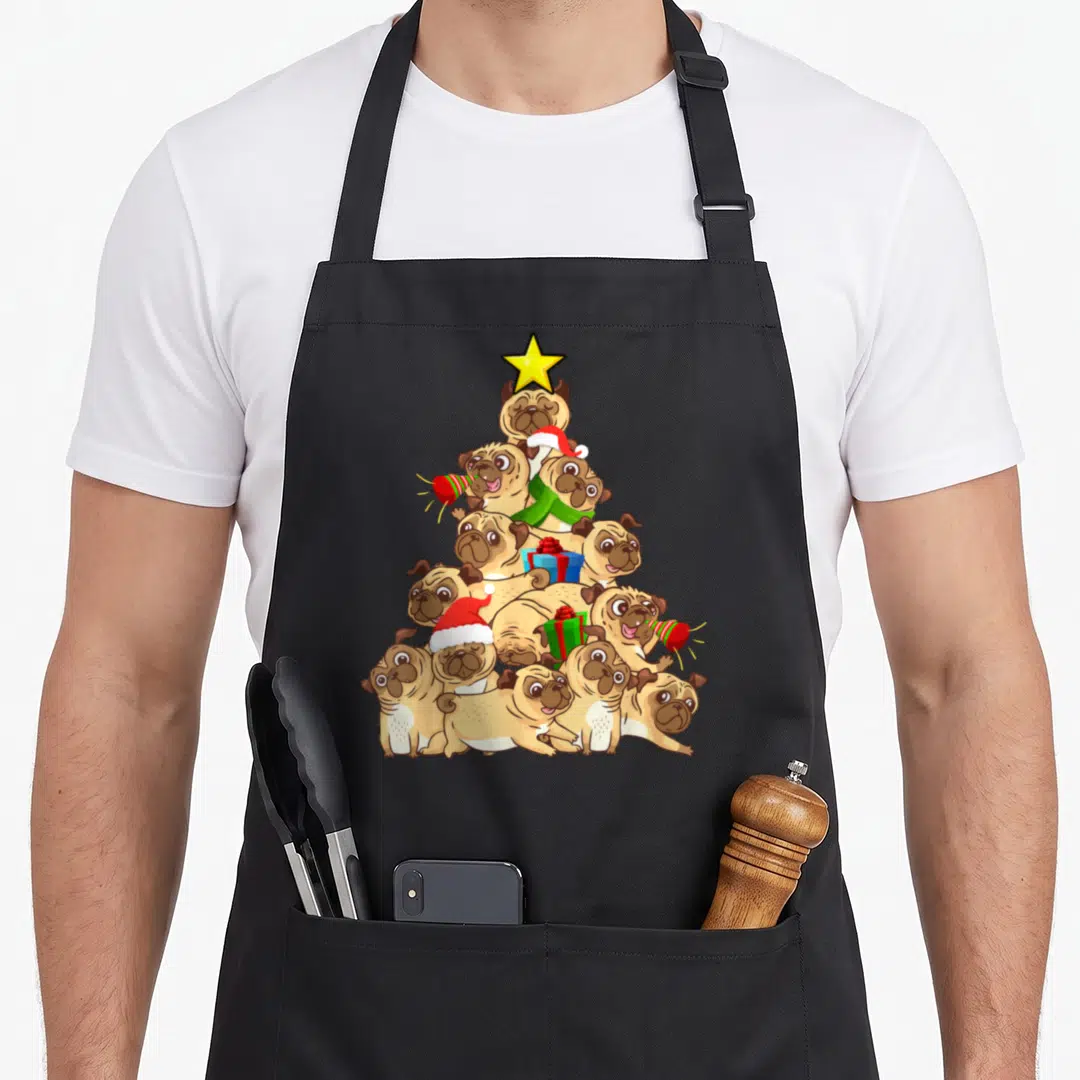 Sweater christmas tree apron - Cartoon tan pugs stacked in a Christmas tree pyramid with yellow star and red green — shown on a black cotton canvas apron against a white background